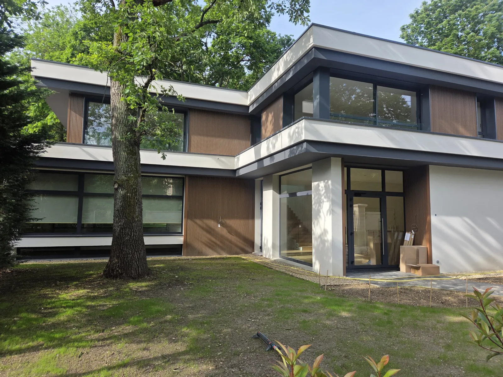 Façade sur jardin en été, bardage bois et étage en débord, maison contemporaine au Vésinet, DSA Architectes